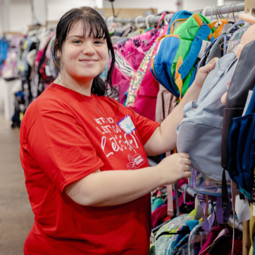 Mom holds hand up to show of rows and rows of clothing for sale at 50 to 90% off retail prices!